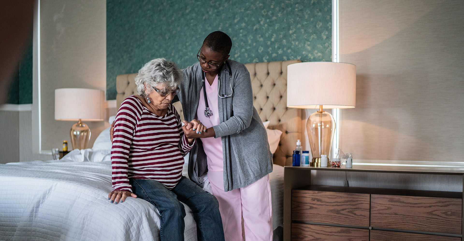 Nurse helping senior lady out of bed